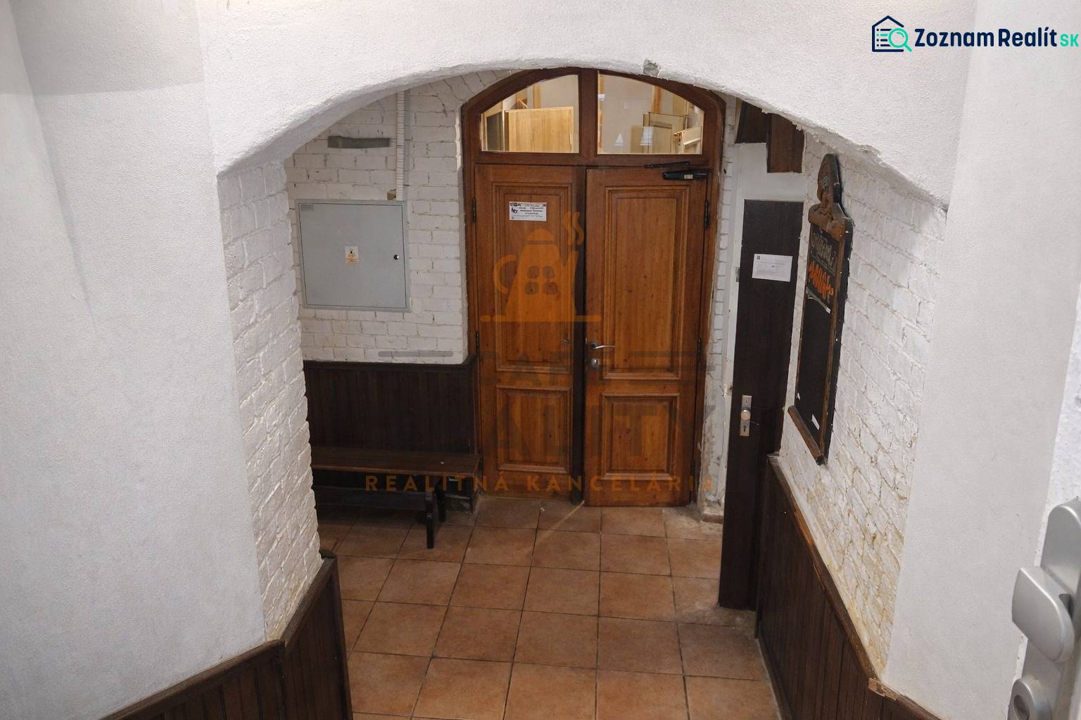 Entrance door in commercial premises with a brick wall and tiled floor.