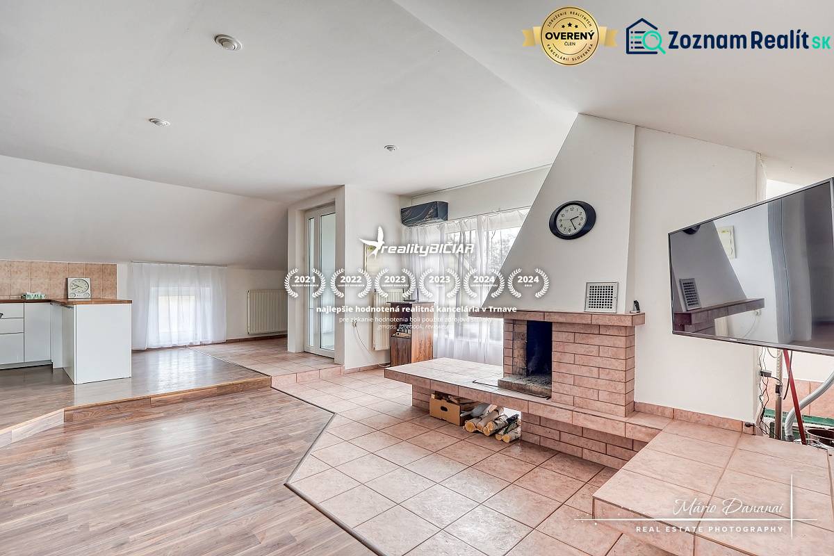 Living room with a fireplace in a family house, floor with wooden decor, spacious windows.