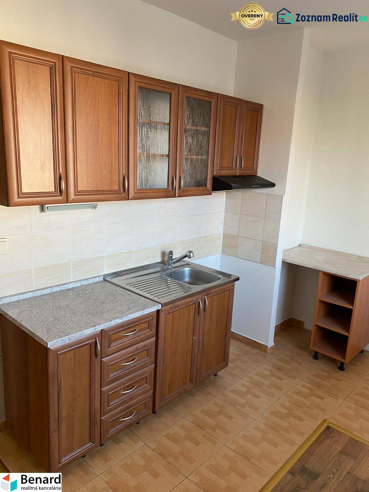 A kitchen with wooden cabinets and a sink in a 3-room apartment, flooring with a wooden decor.