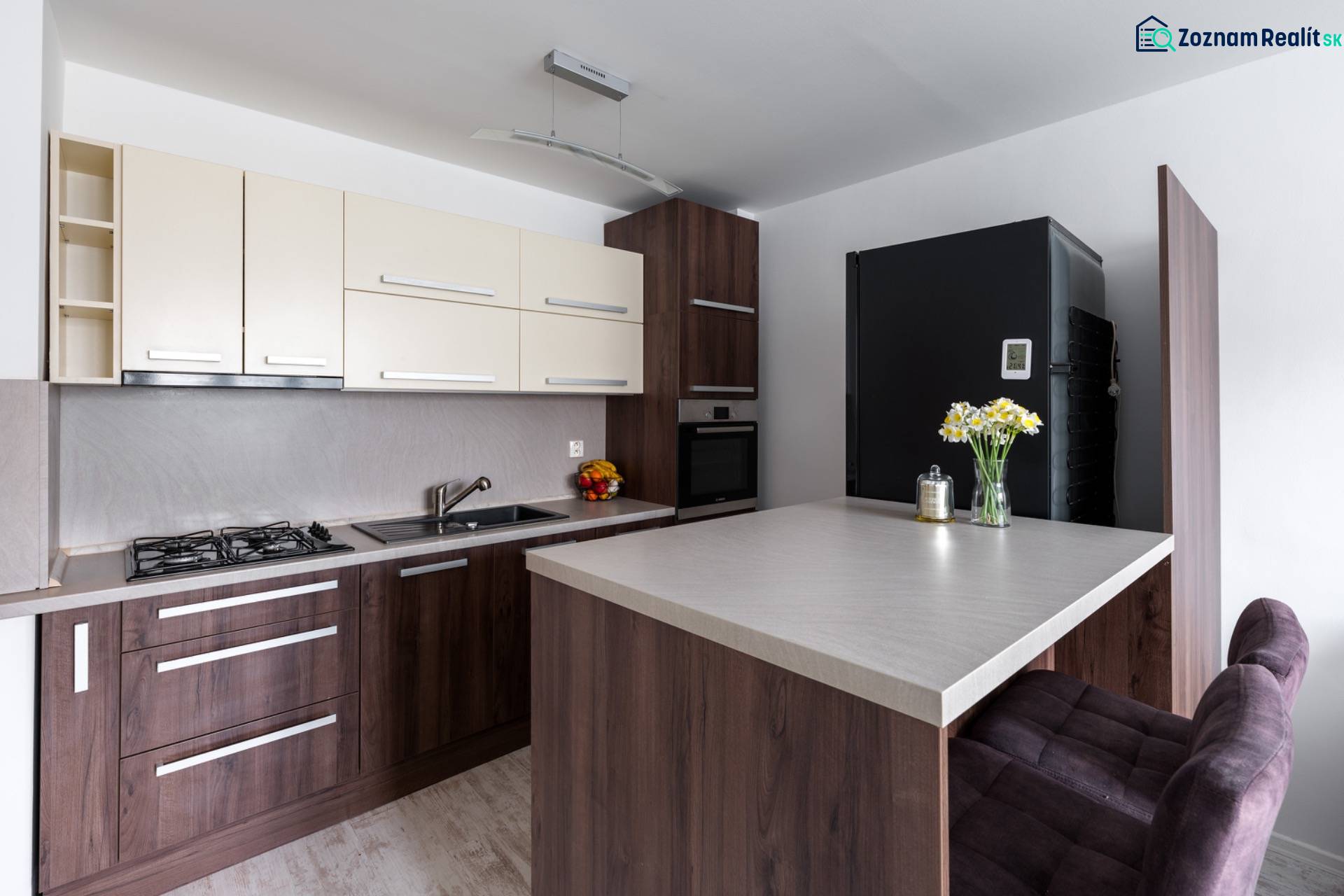 A kitchen in a 2-room apartment with a wooden decor floor, a bar counter, and modern equipment.