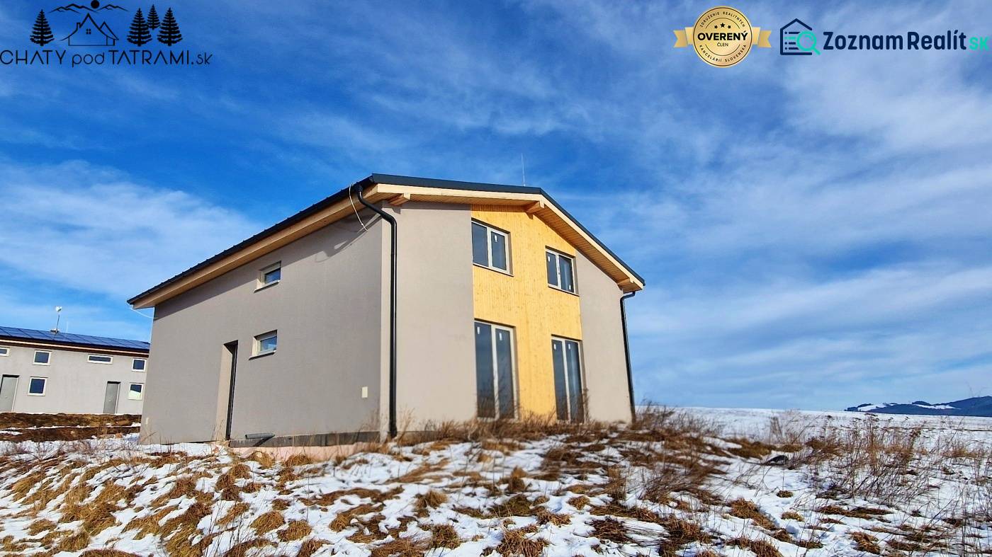 A cottage in Dolná Lehota with wooden decor, a snowy plot, and a cloudy sky.