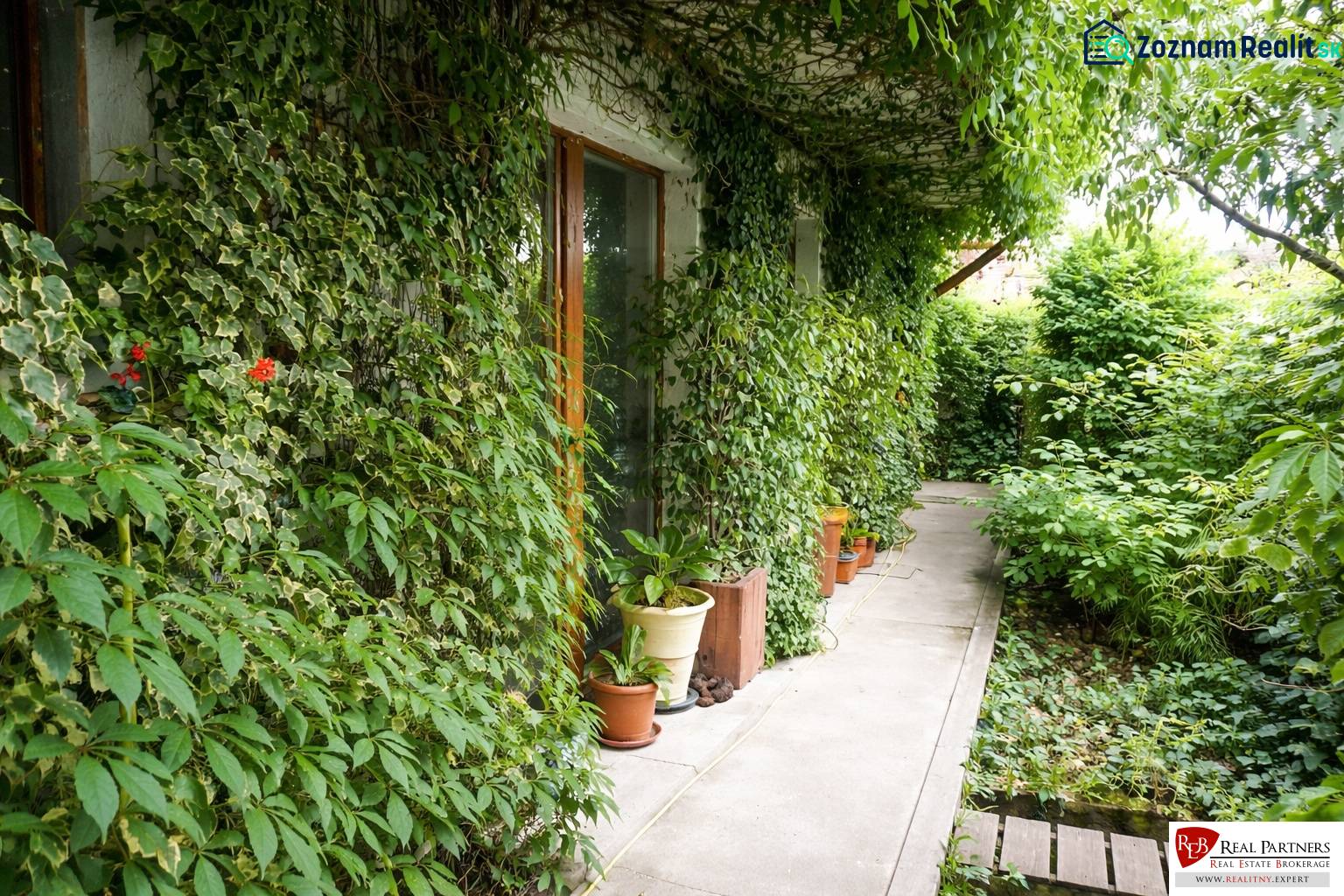 The garden of a 3-room apartment on Šancová Street in Pezinok with lush greenery and a pathway.