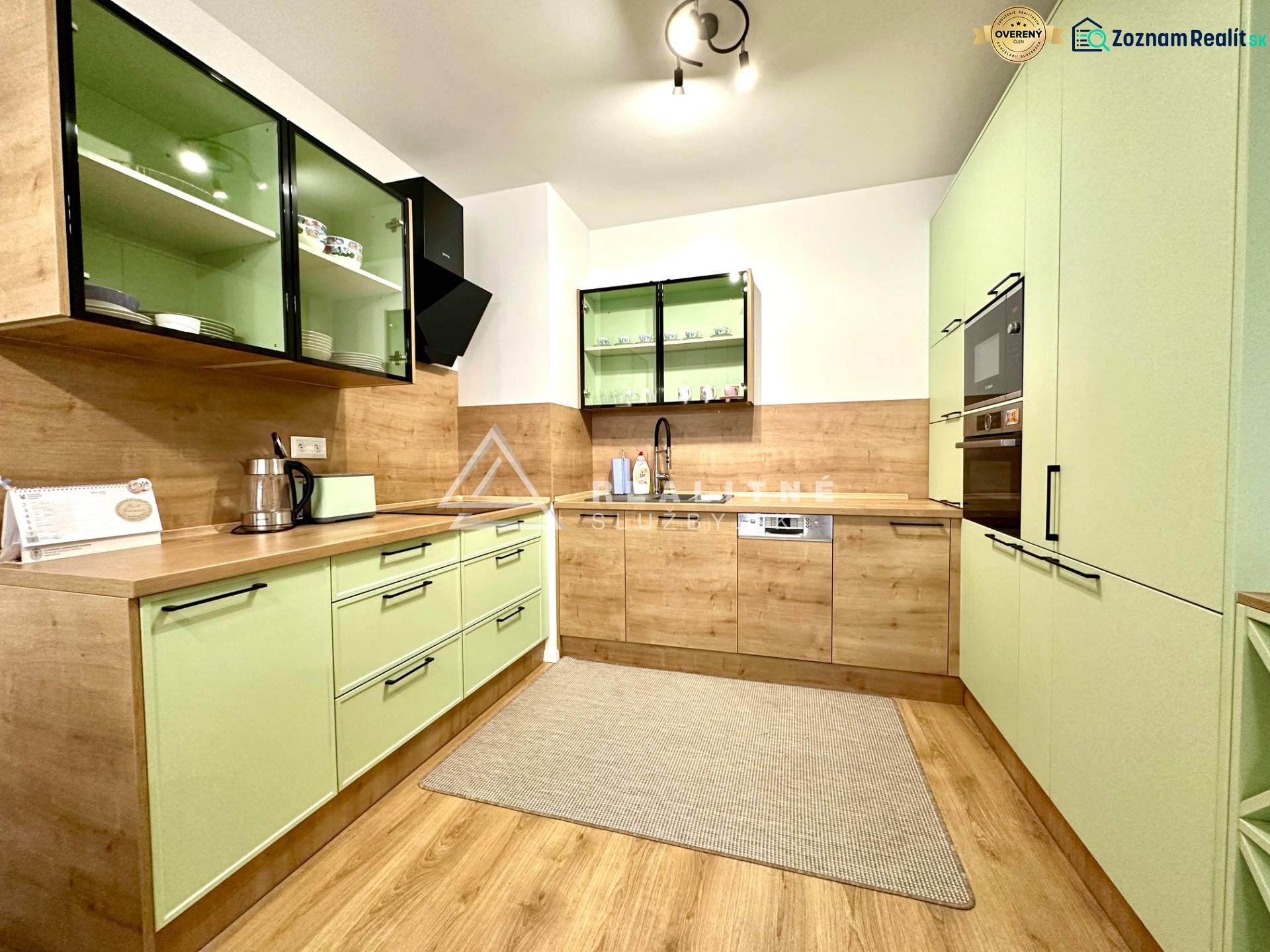 A kitchen in a 2-room apartment with pastel cabinets and a wooden decor floor.