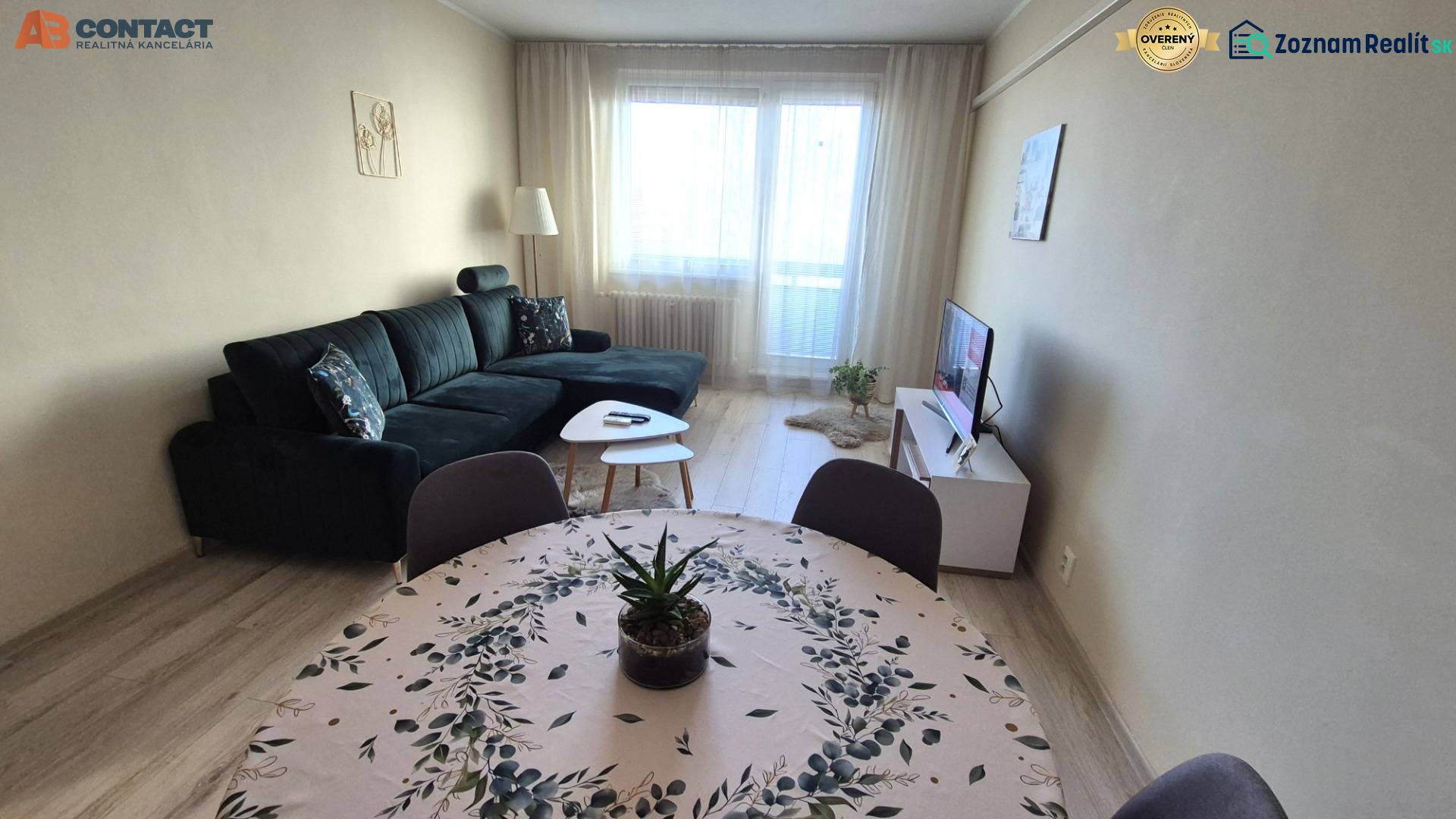 Living room with a dark sofa, dining table, and wooden decor flooring in a 2-room apartment.