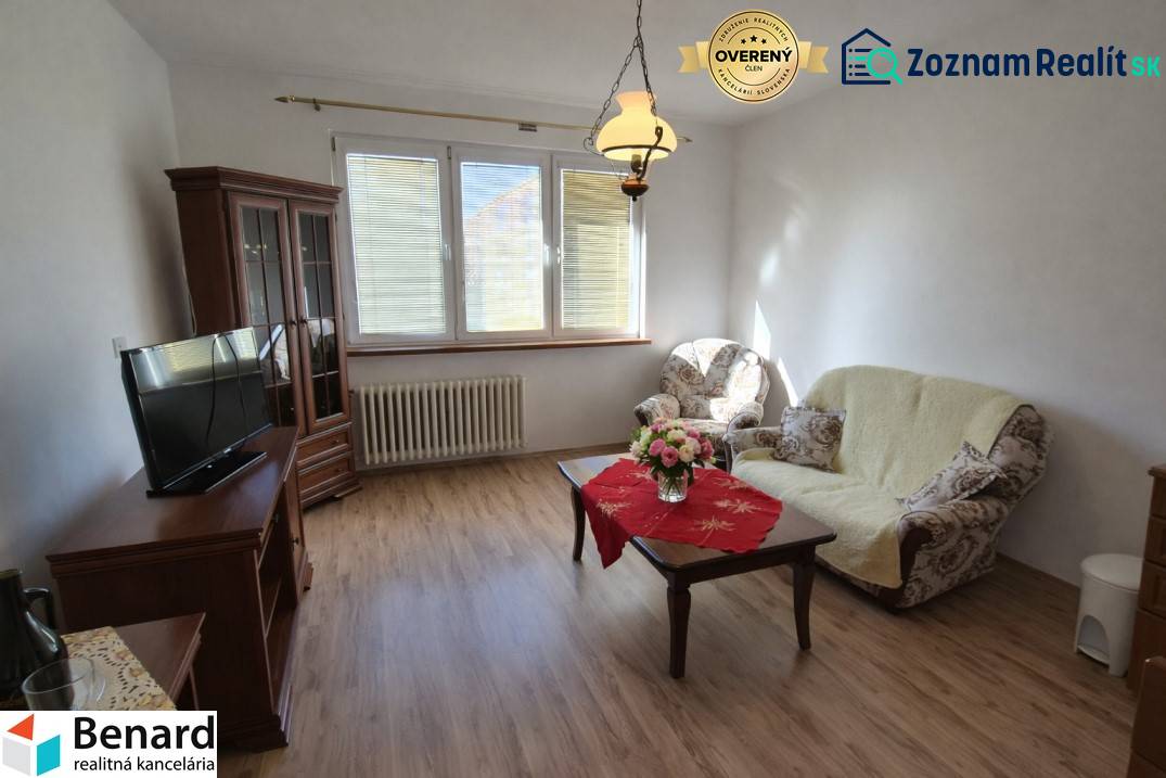 Living room in a two-room apartment with a wooden decor floor, comfortable furniture, and a decorative table.
