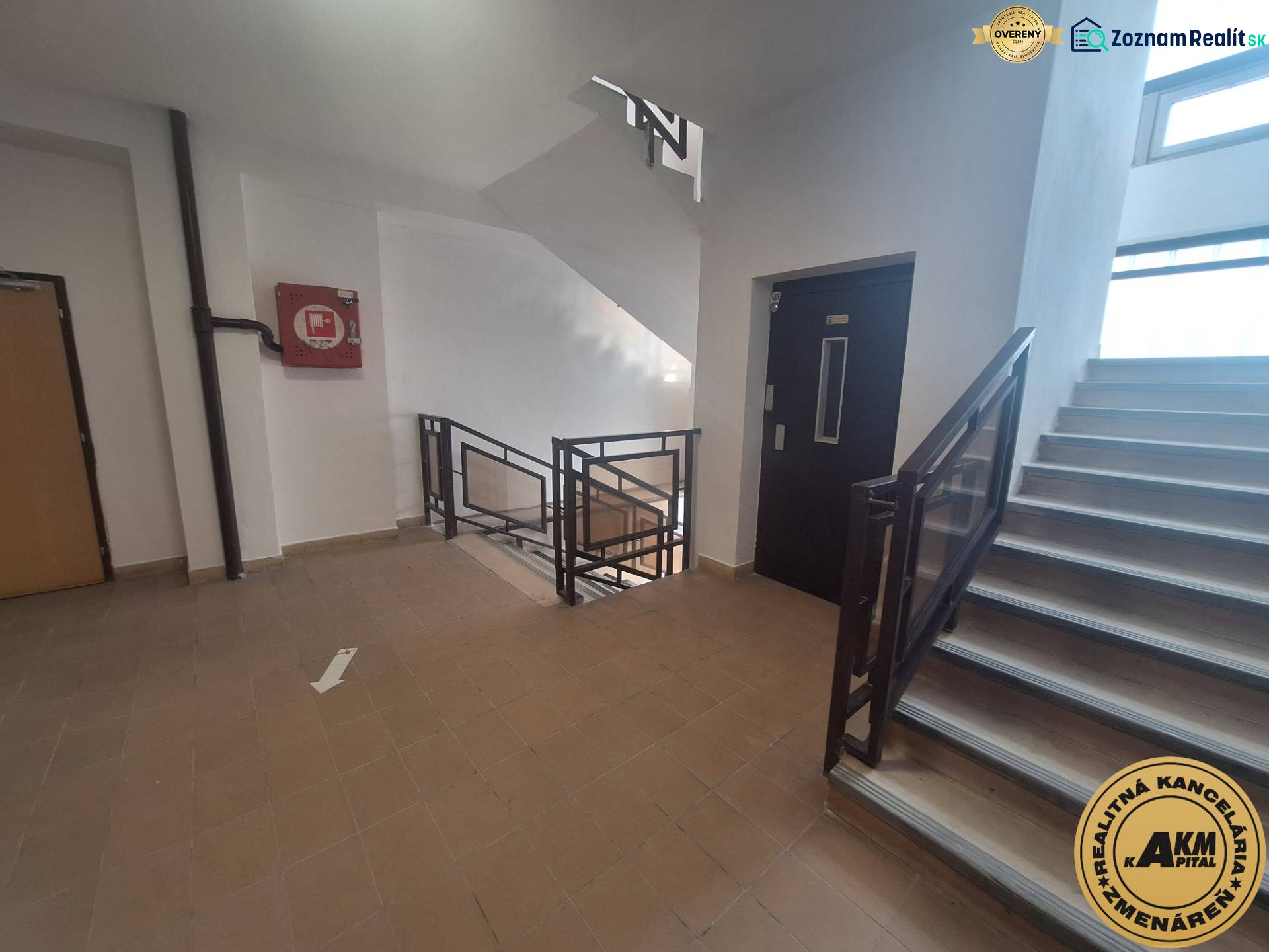 A corridor in commercial premises with a staircase and an elevator, tiled floor.