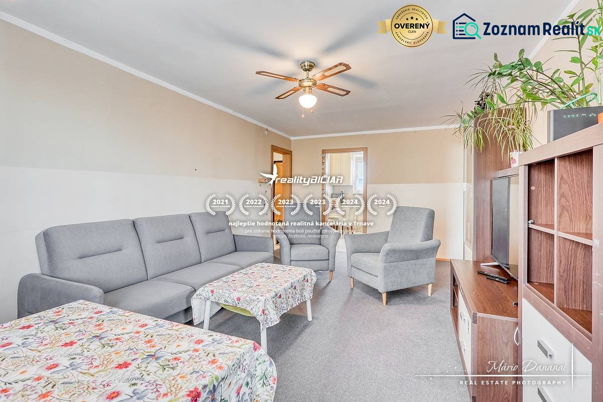 Living room in a 4-room apartment with a gray sofa, table, and ceiling fan.