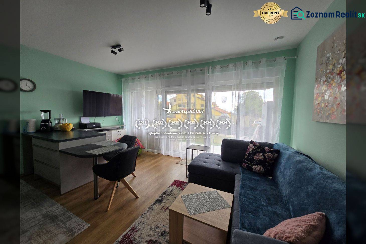 Living room in a holiday apartment with wood-patterned flooring, a sofa, and a TV.