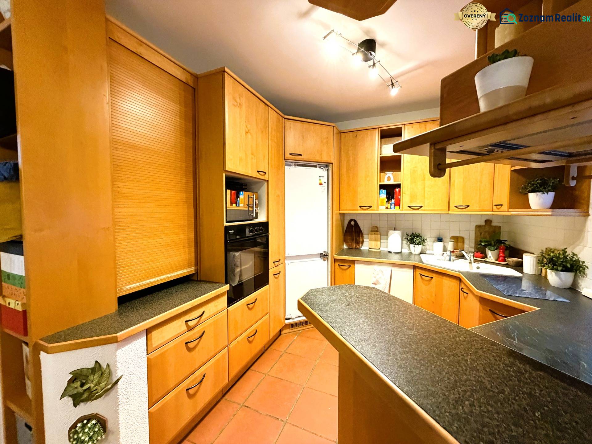 A kitchen in a 3-room apartment with a corner unit and a floor with a wood decor.