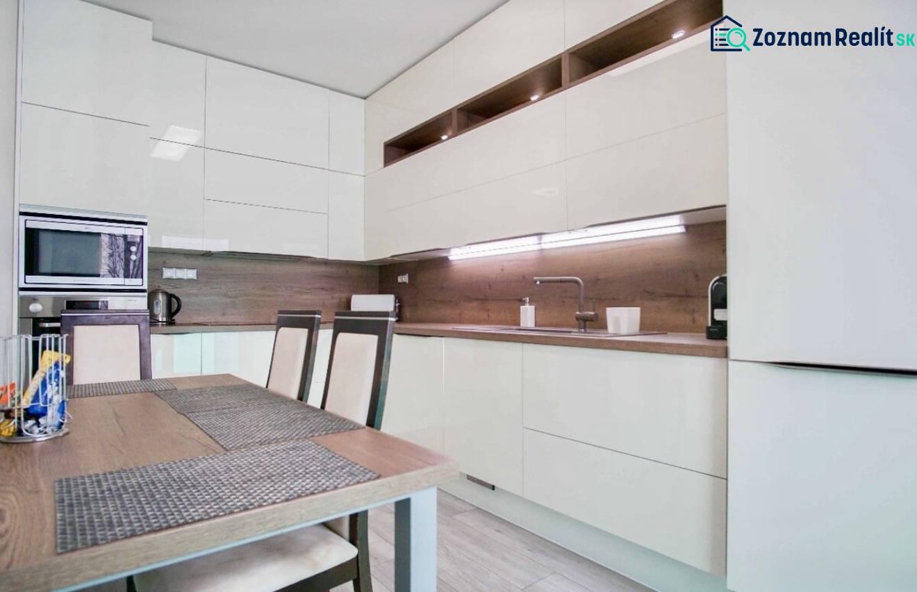 A kitchen in a 3-room apartment with glossy cabinets and wooden wall decor.