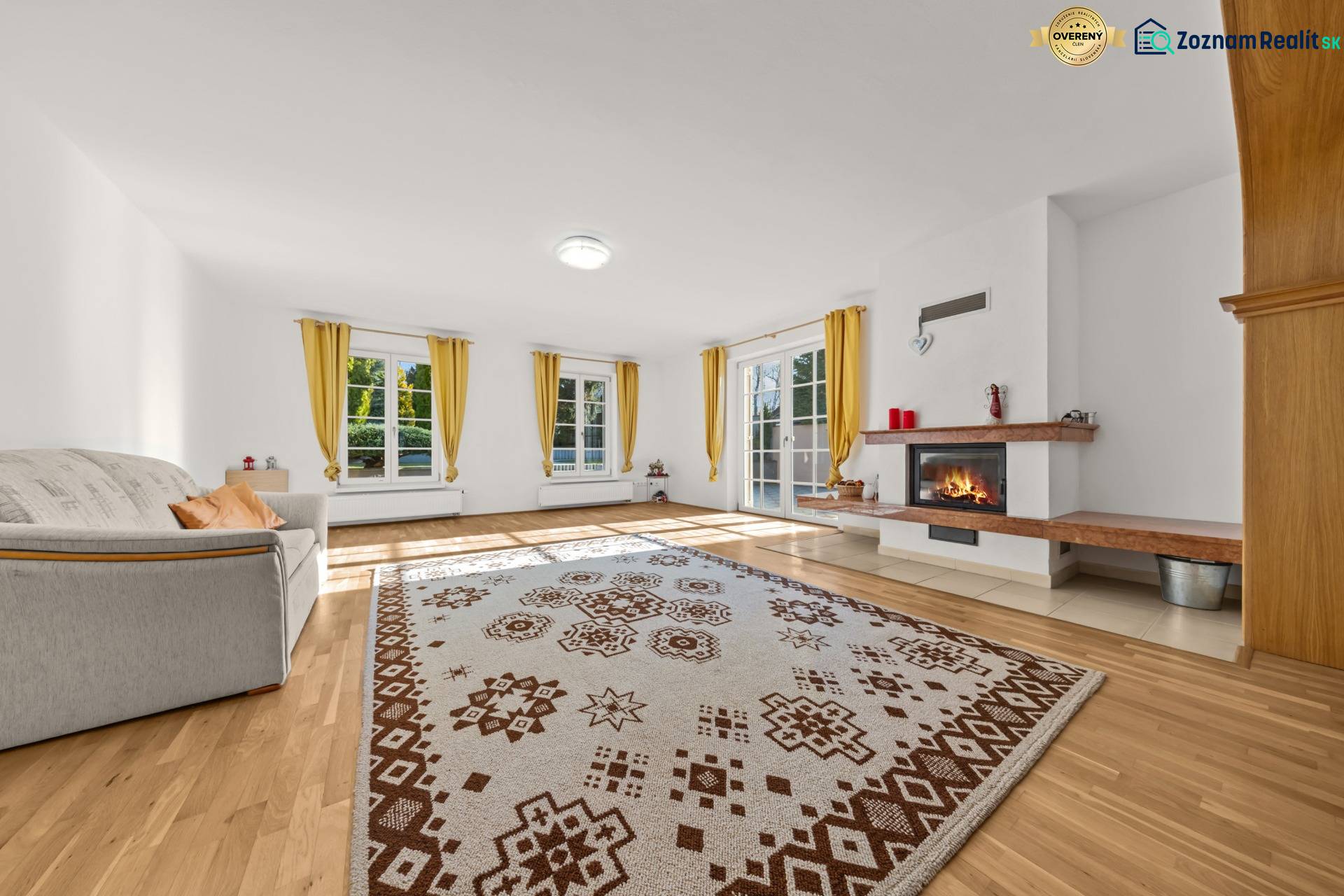 Living room with a fireplace, sofa, and wood-patterned flooring in a family house.