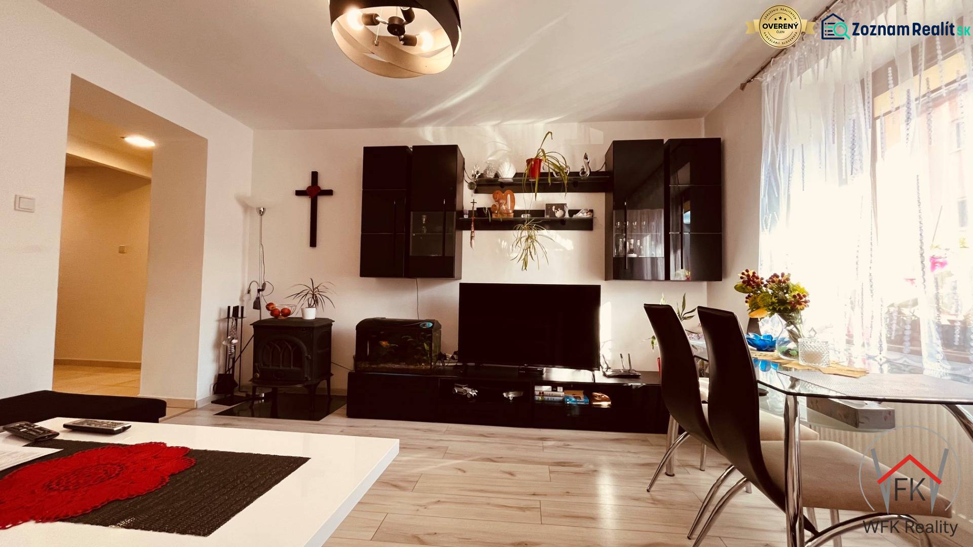 Living room of a three-room apartment with a wooden decor floor, dining table, and wall unit.