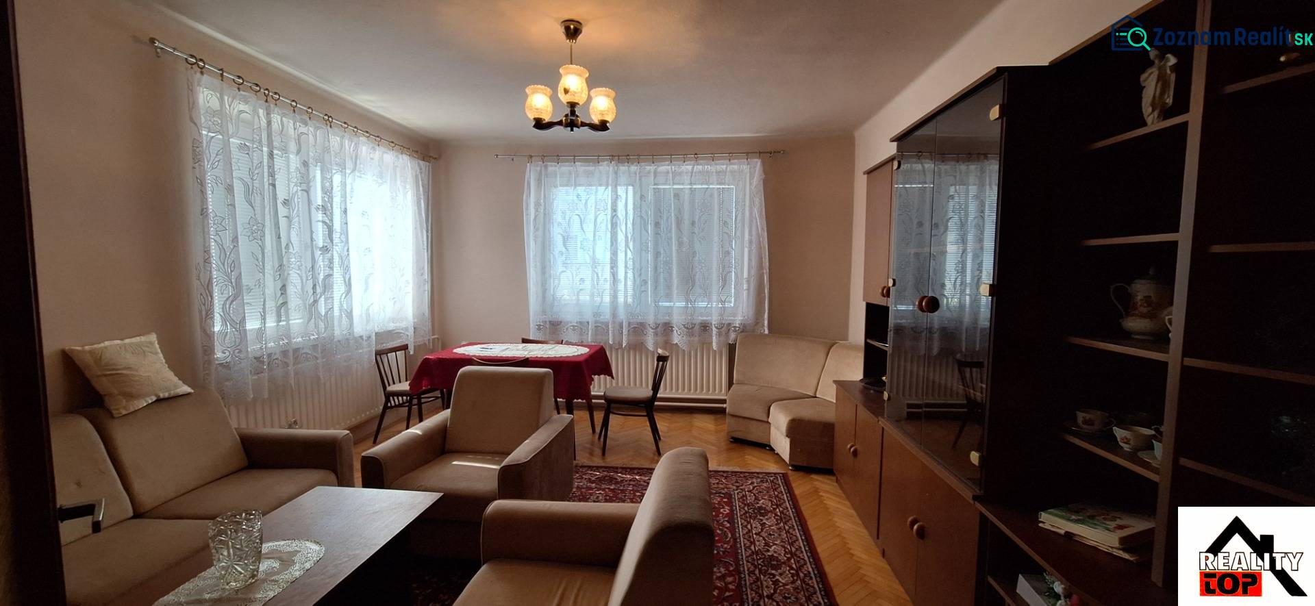 Living room with carpets, curtains, a sofa, and a wooden decor floor in a family house.