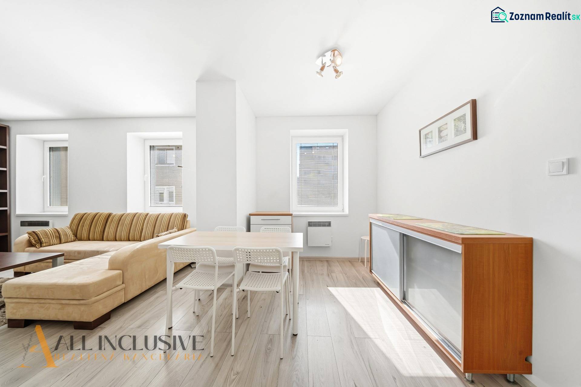 A bright living room in a 3-room apartment with wood-patterned flooring and comfortable seating.
