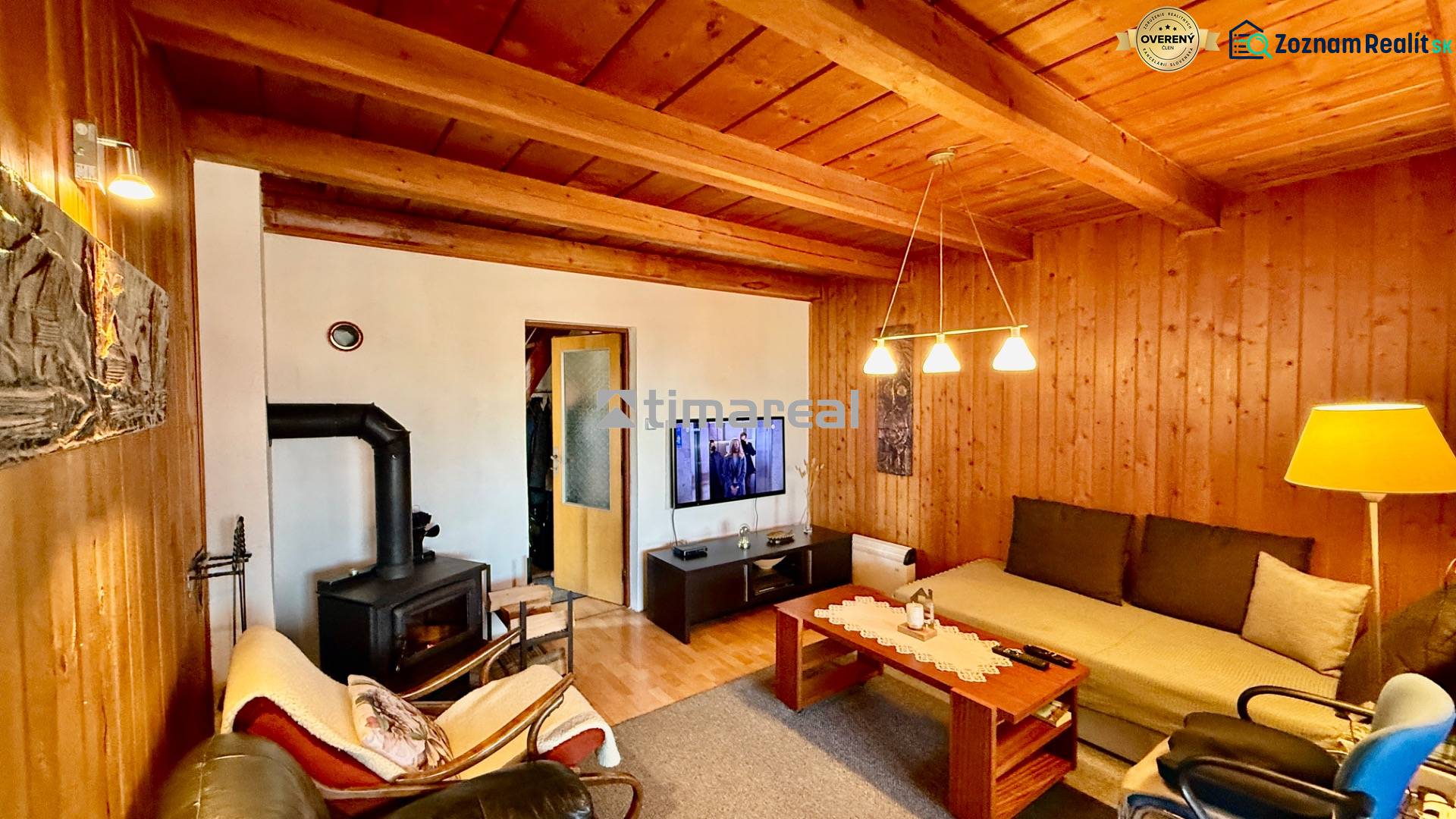Living room in a family house with a wooden ceiling, fireplace, and comfortable seating.