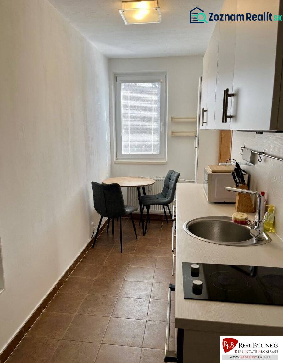 A kitchen in a 2-room apartment with a sink, stove, and a table with chairs.