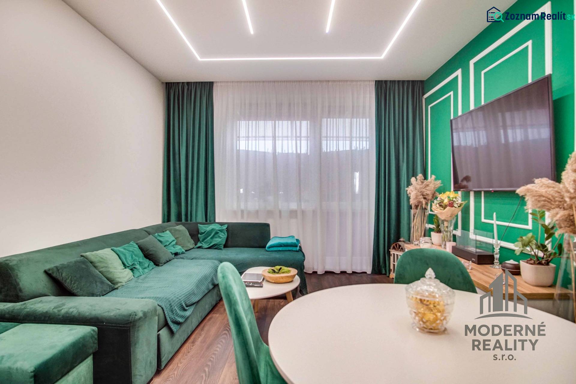 Living room in a two-room apartment with a sofa and decorative green elements.