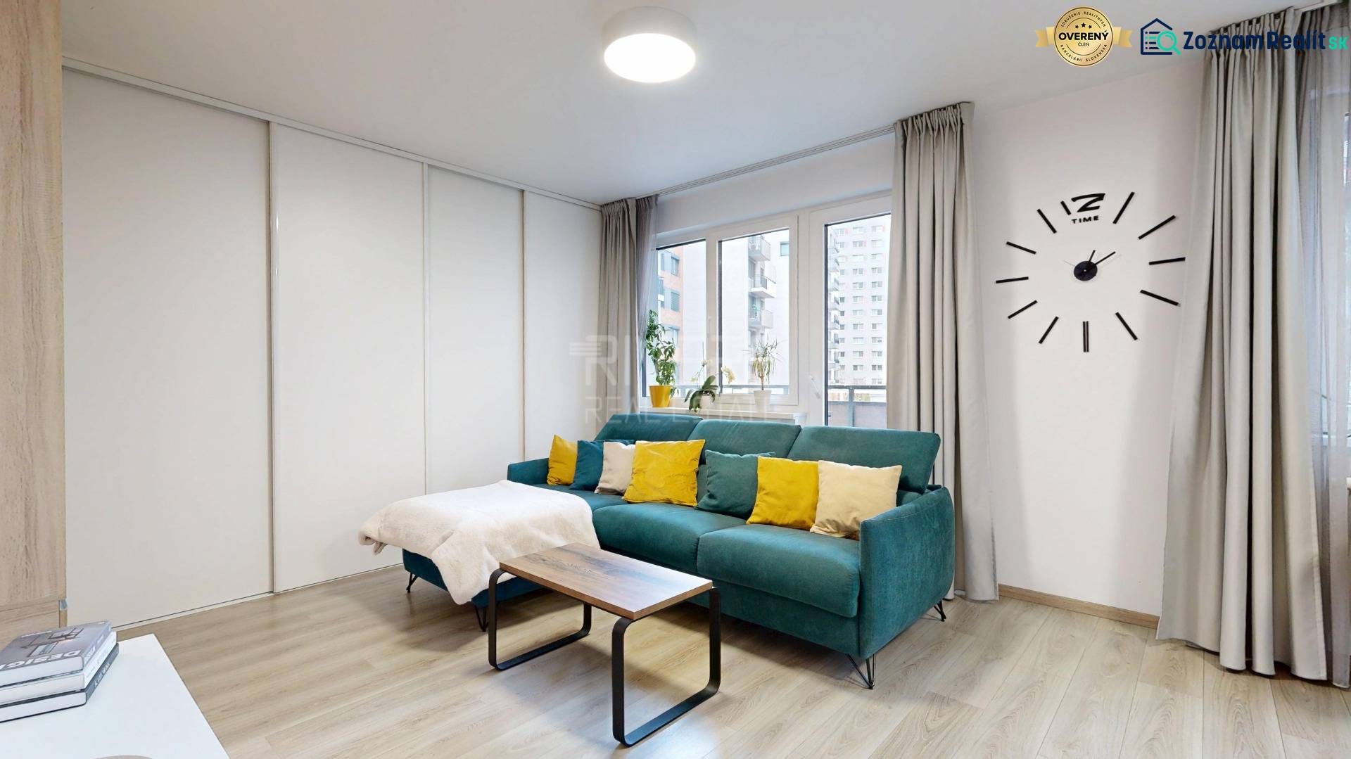 Living room with a turquoise sofa and wood-patterned flooring in a studio apartment.