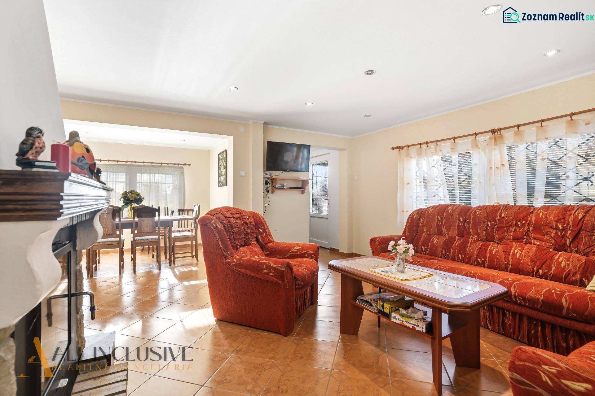 Living room in a cottage with an orange sofa and a fireplace, floor with wood decor.