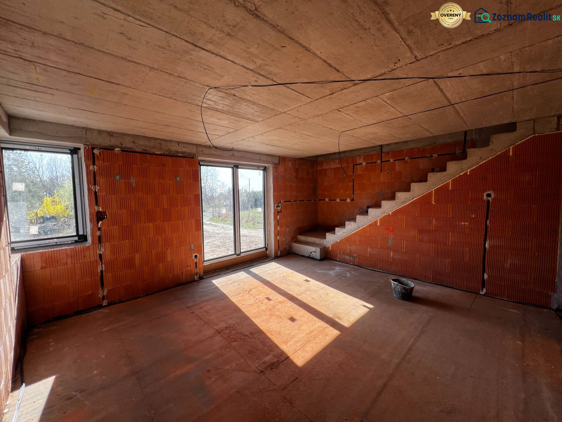 Unfinished interior of a family house with brick walls and a staircase.