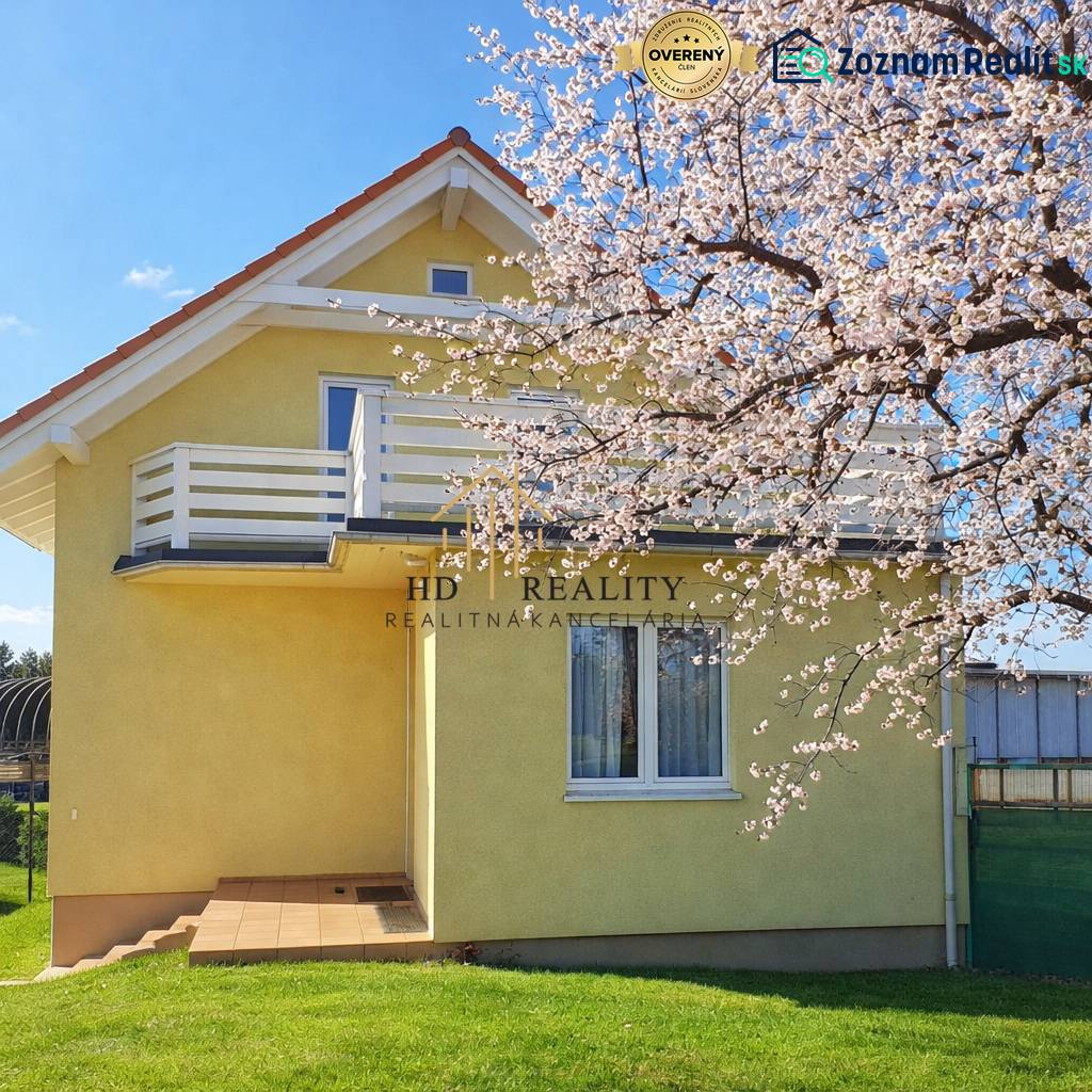 A family house on Poprad Street in Poprad with a balcony and a blooming tree in the garden.