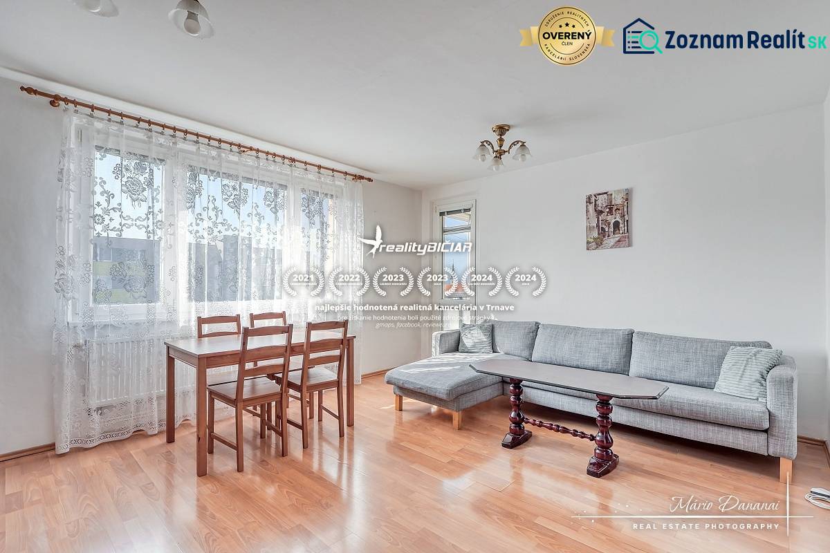 Living room in a three-room apartment with a wooden decor floor, dining table, and gray sofa.