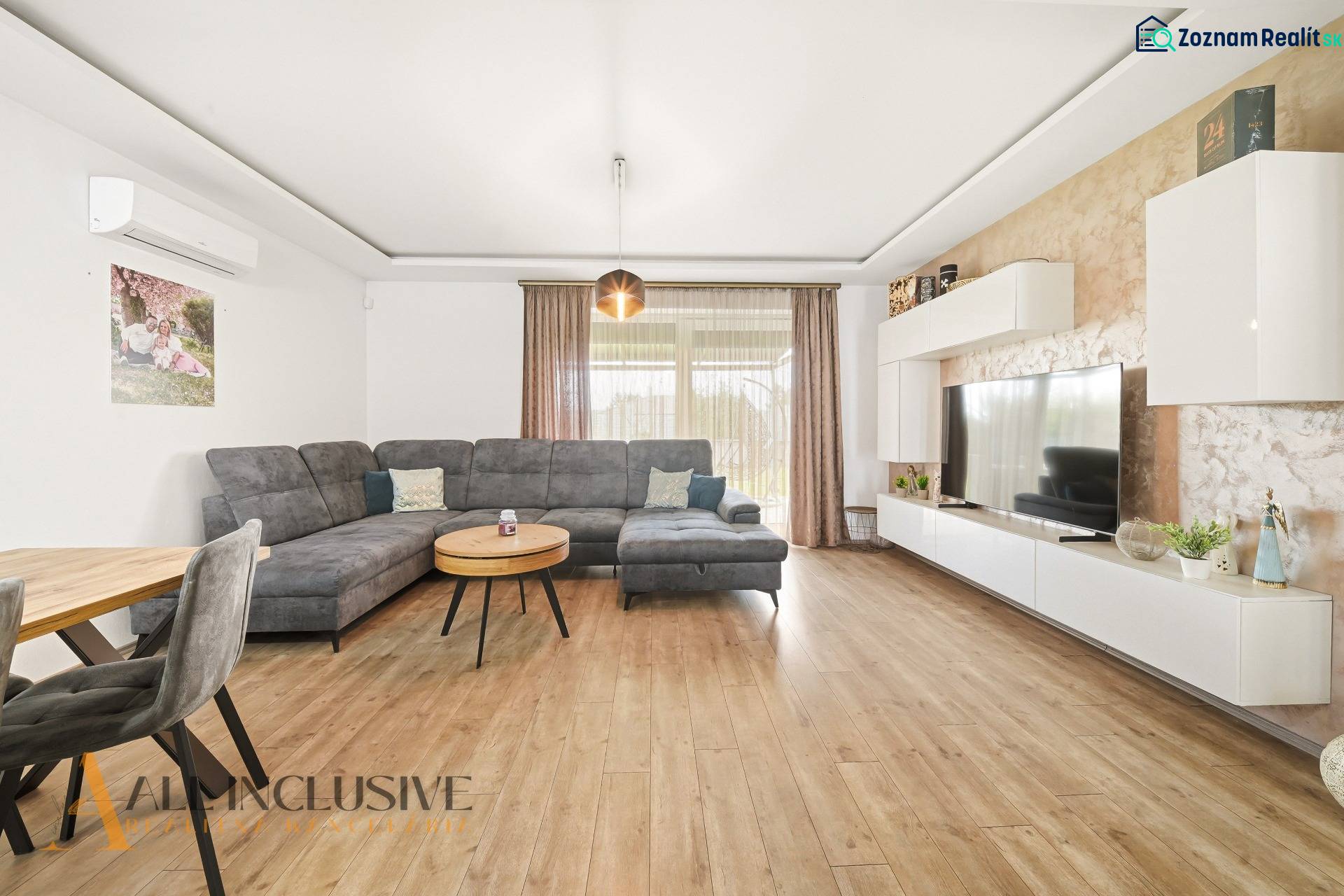 Living room of a family house with a comfortable sofa and a wooden-patterned floor.