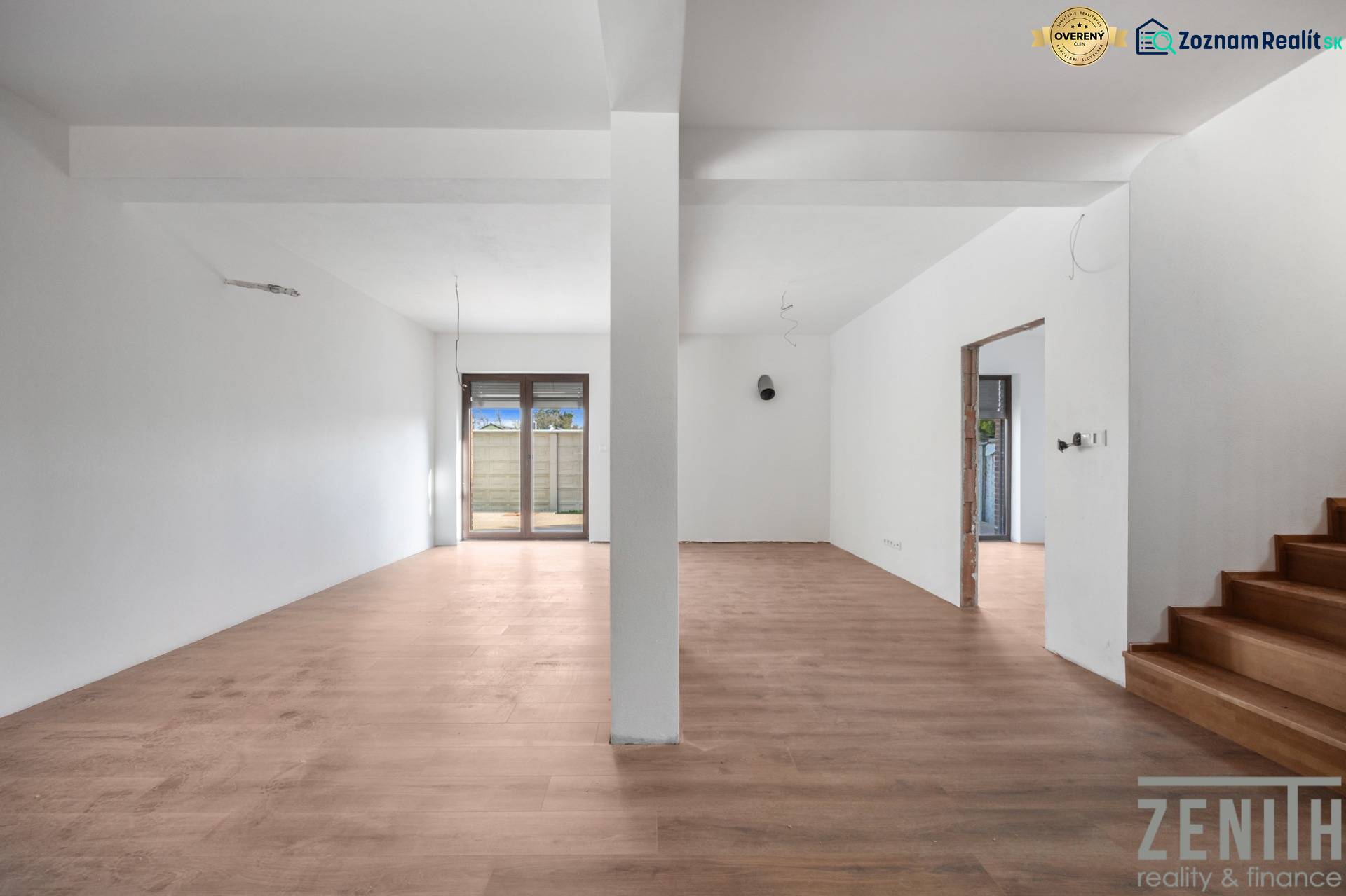 A spacious room in a family house with a wooden decor floor and glass doors.