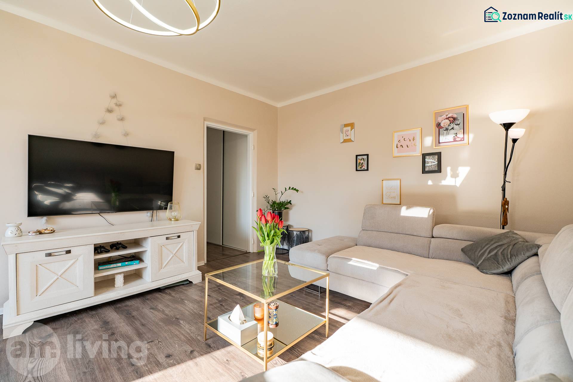 Living room of a two-room apartment with a sofa, table, and floor with wood decor.