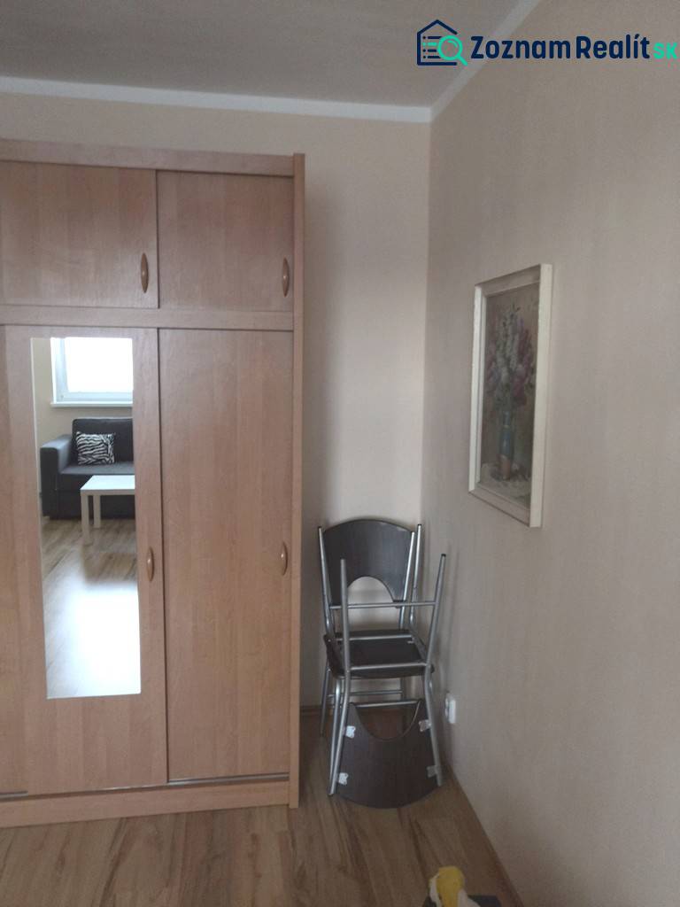 Wardrobe with a wooden decor floor in a studio apartment, cream walls, folding chairs.