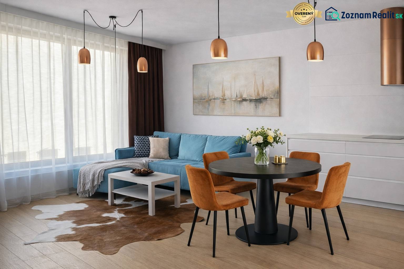 Interior of a 2-room apartment with a blue sofa, dining table, and wooden decor flooring.