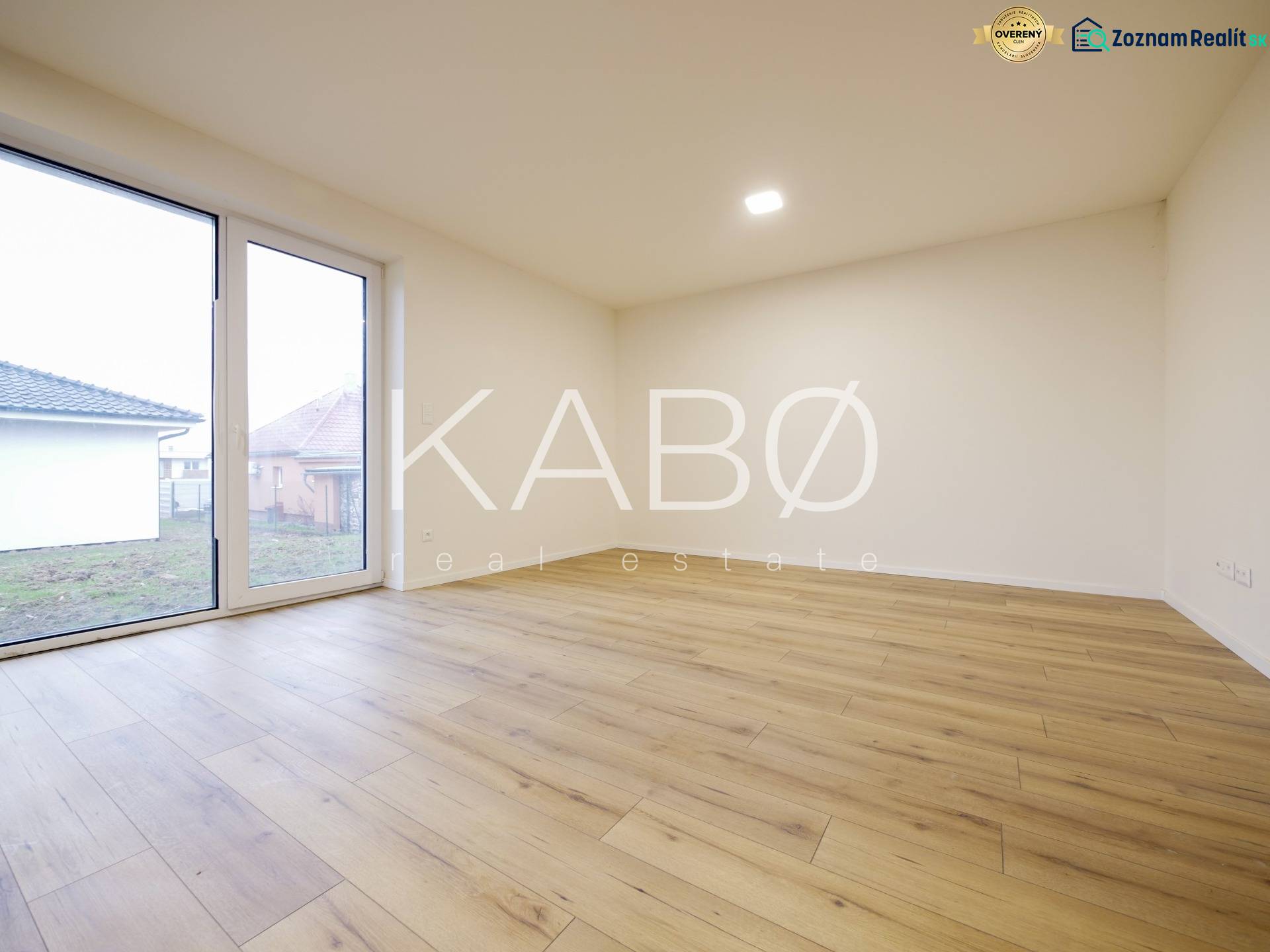 A room in a family house with a wooden decor floor and large windows.