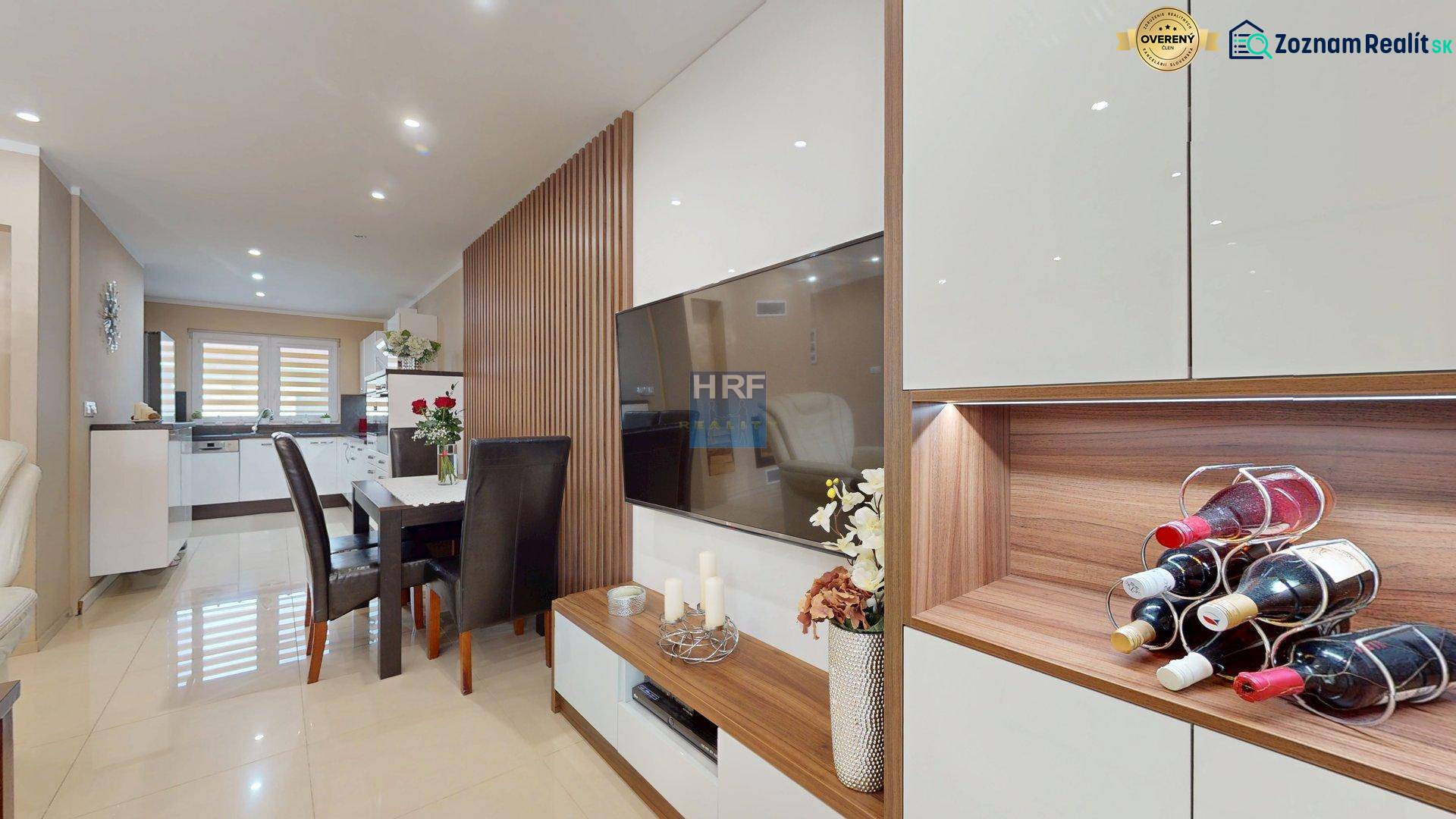 Living room and kitchen in a family house with a wood-patterned floor.