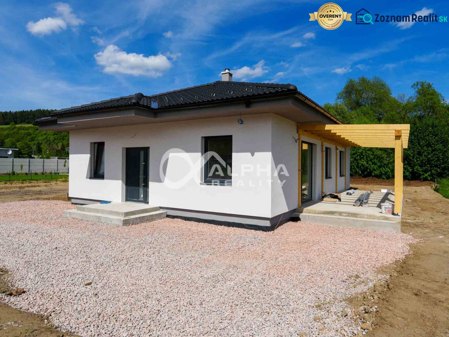 A family house in Harichovce with a gravel area and a wooden pergola in the yard.