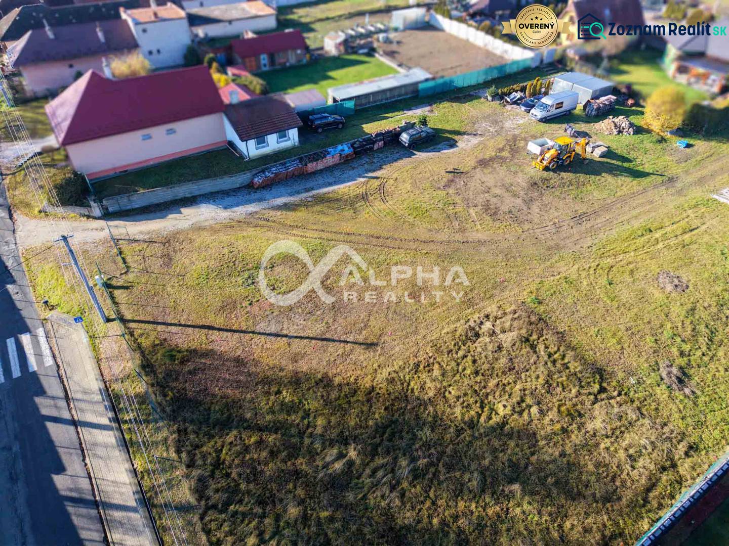 Lands in Spišské Tomášovce for housing, surrounding houses, construction equipment, grassy area.