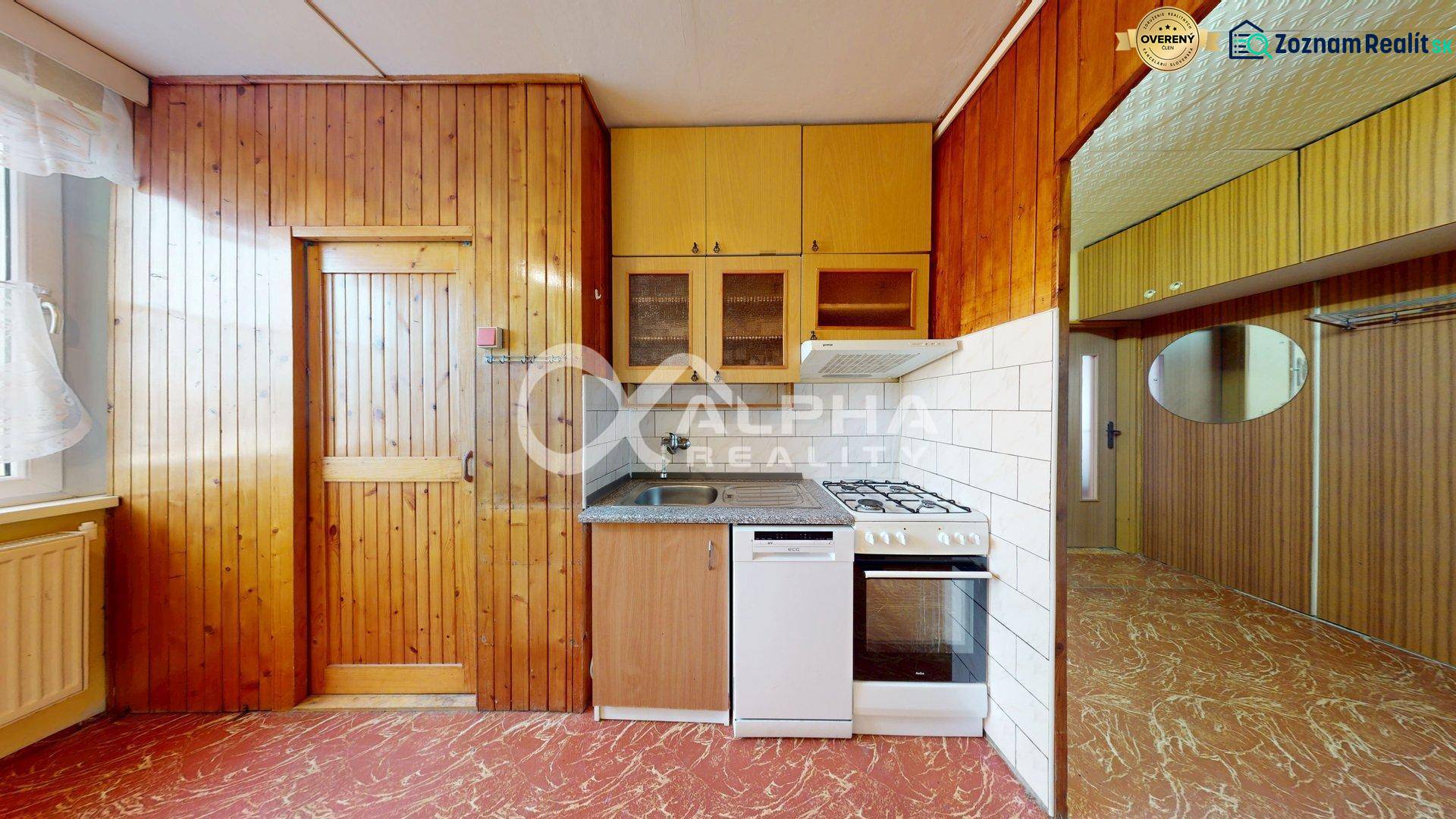 A kitchen in a 3-room apartment with wooden paneling and a kitchen unit.