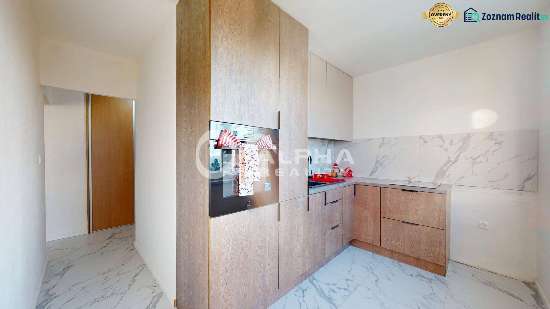 A kitchen in a 2-room apartment with a wooden decor floor and marble walls.