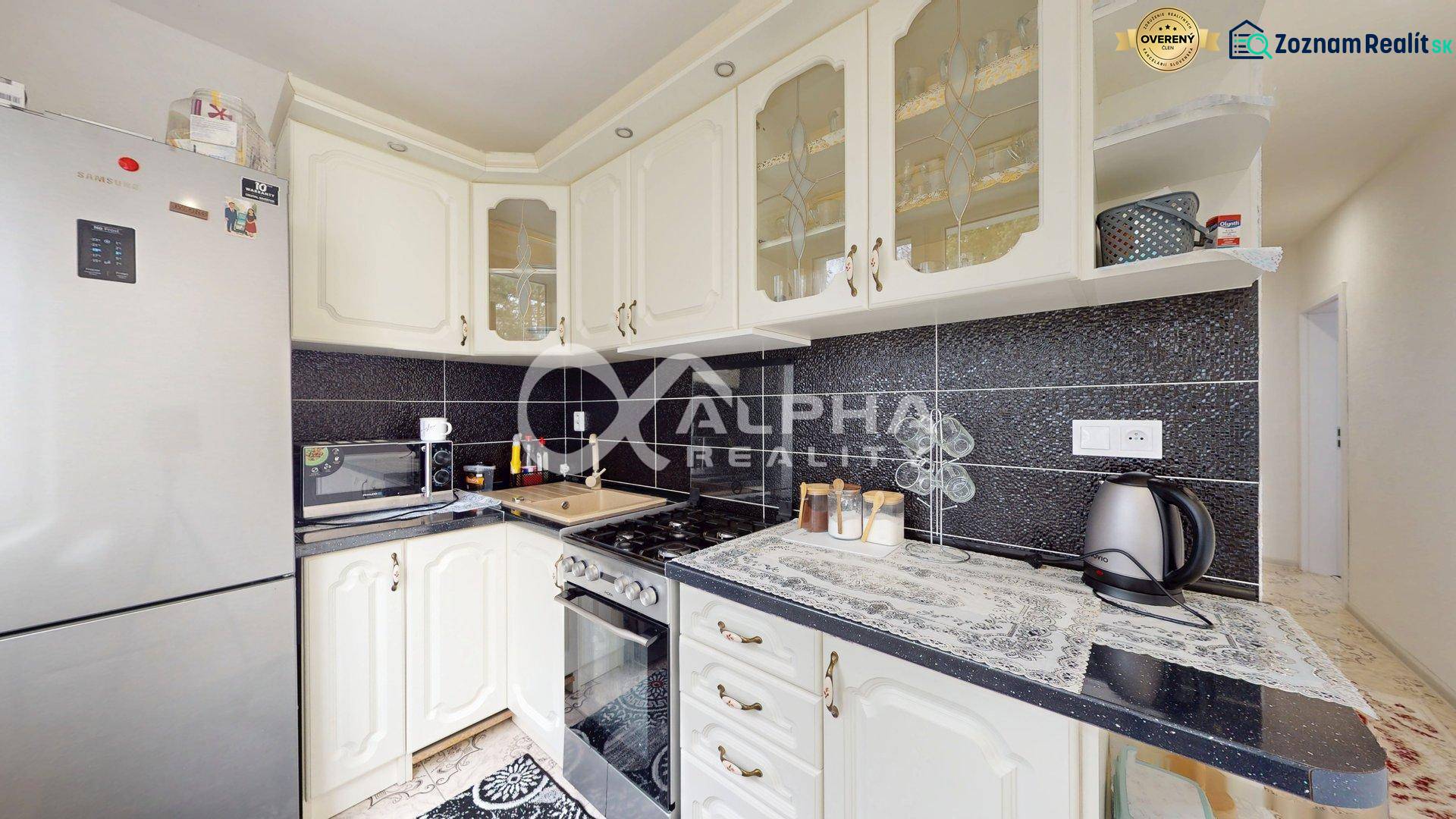 A kitchen in a 2-room apartment with black tiles and light cabinets.