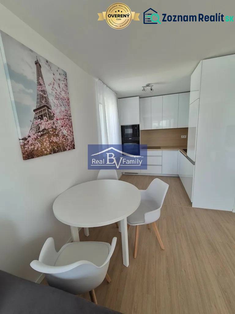 A kitchen in a 2-room apartment with a wooden decor floor and a dining table.