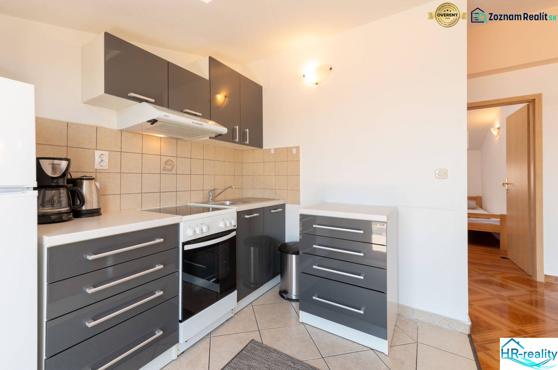 A kitchen in a holiday apartment with dark gray cabinets and tiled flooring.