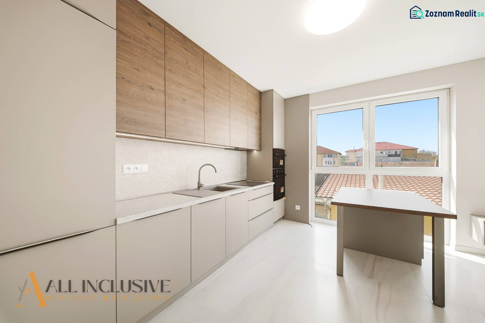 A kitchen in a 2-room apartment with a wooden decor floor and a large window.