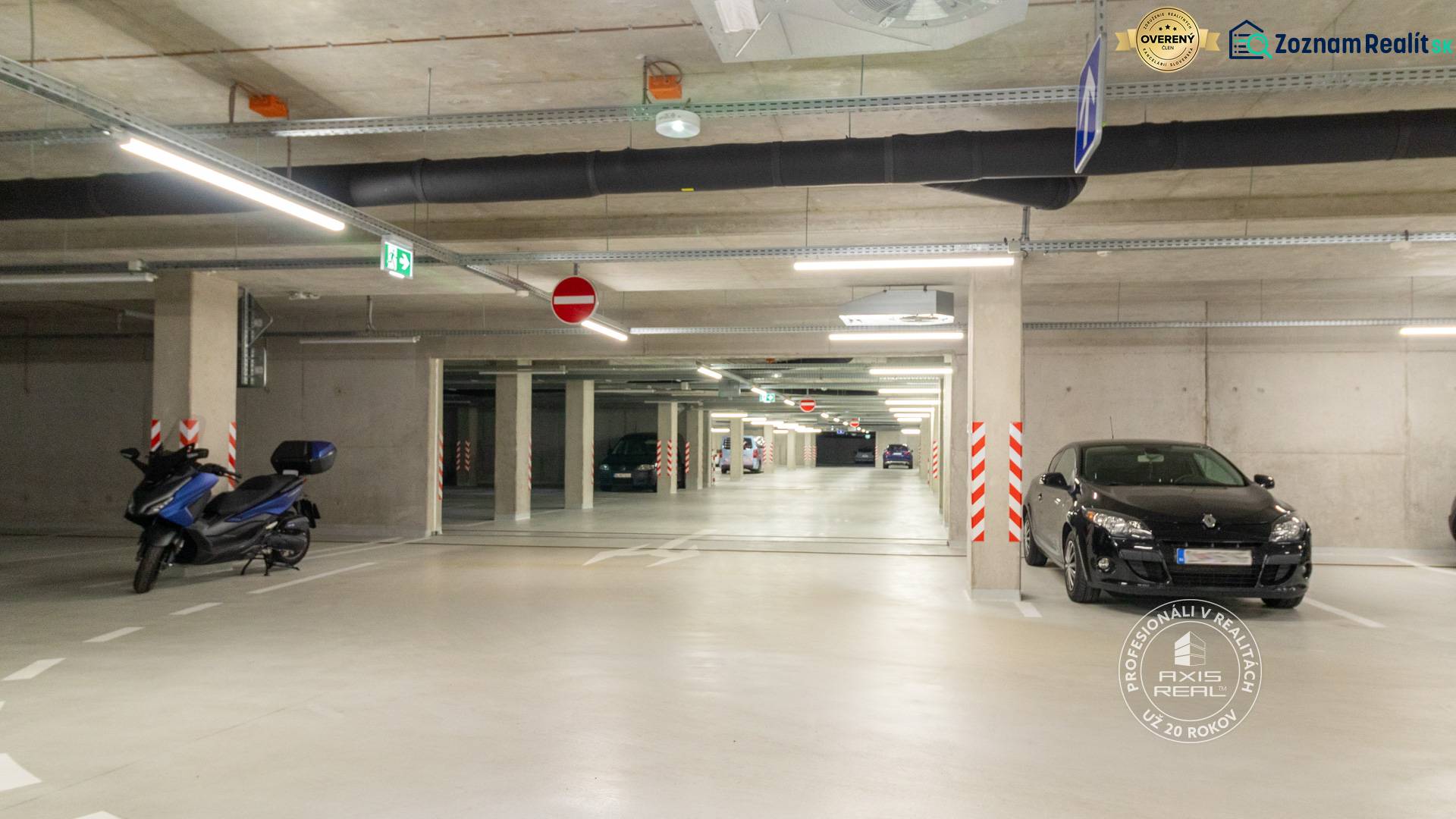 Parking garage with cars and a motorcycle, underground lighting, the space gives a clean impression.
