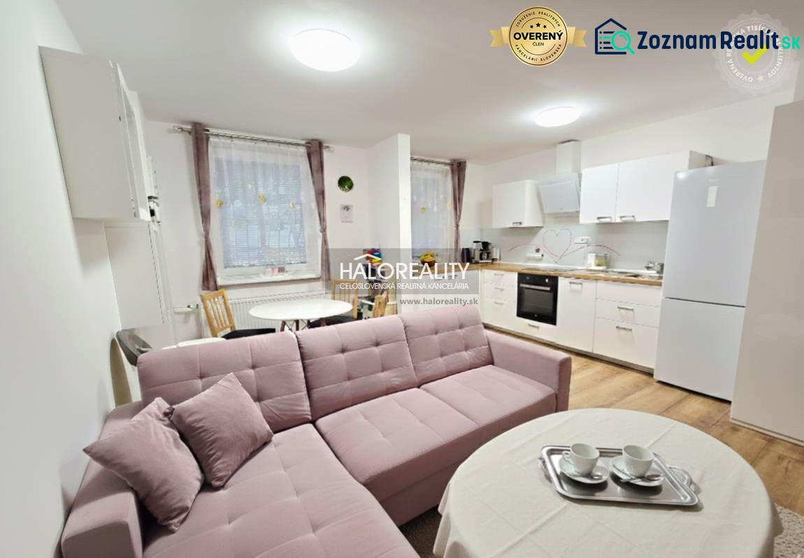 Living room in a three-room apartment with a corner sofa and kitchen, wooden decor flooring.