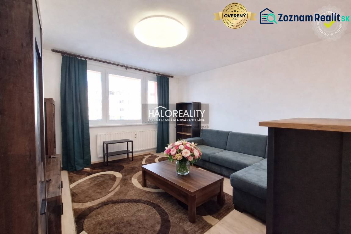 A living room with a sofa, carpet, and fresh flowers in a 3-room apartment.
