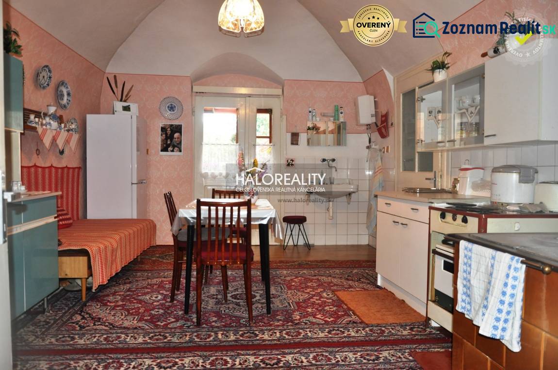 A kitchen in a family house with vintage decor, a wooden cabinet, and carpets.