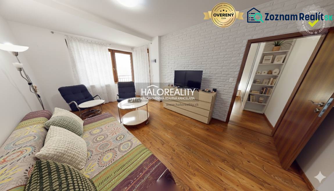 Living room with a sofa, TV, and wood-patterned flooring in a three-room apartment.