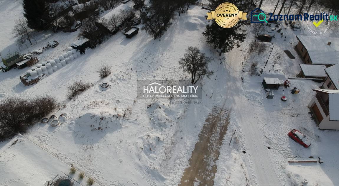 Snow-covered residential lands in Liptovské Beharovce surrounded by trees and buildings.