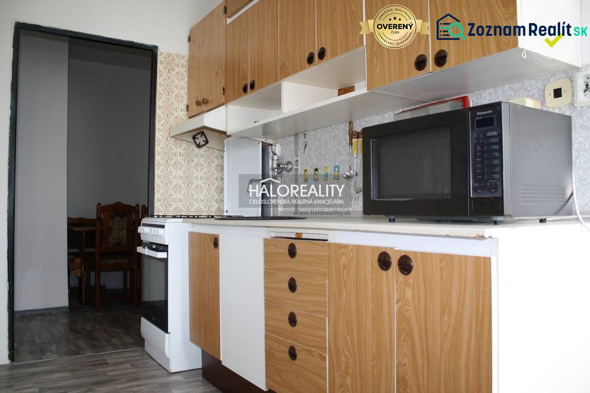 A kitchen in a 2-room apartment with a wooden decor floor and a vintage backsplash.