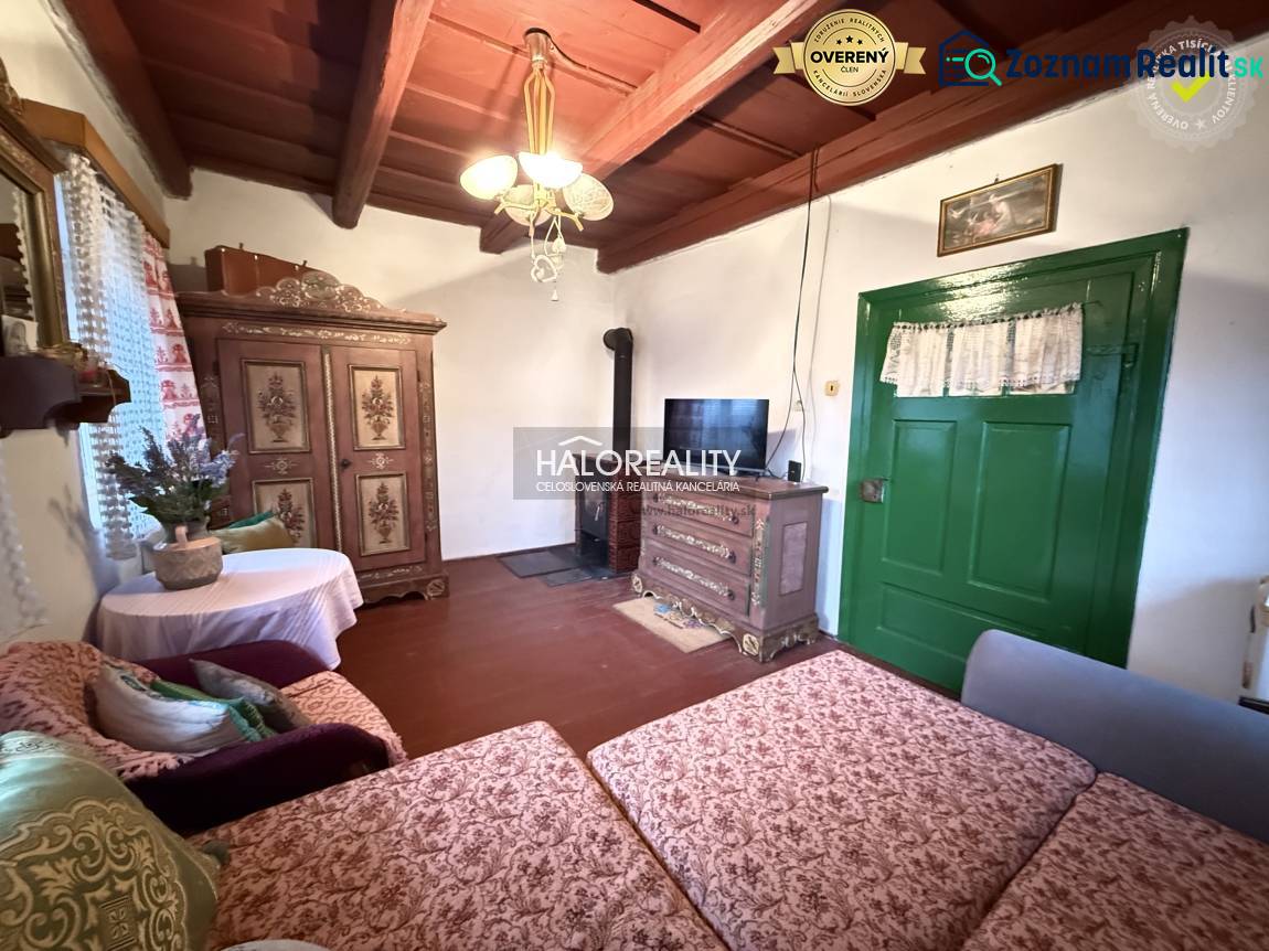 Rustic interior of a cottage with wooden beams, antique furniture, and green doors.