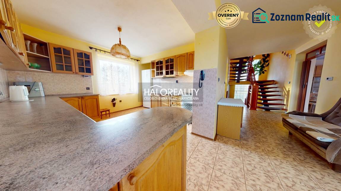 A kitchen in a family house with a living room, staircase, and yellow walls.
